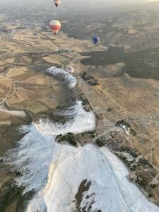 two hot air balloons flying over the water at Manzara Camping in Pamukkale