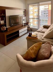 a living room with couches and a flat screen tv at Aconchego e Estilo na Barra in Rio de Janeiro