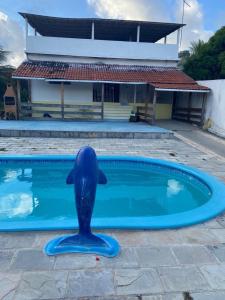 a blue dolphin statue in front of a swimming pool at Casa de praia com piscina in Cabo de Santo Agostinho