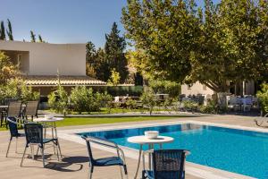 a swimming pool with chairs and tables next to a house at Sofi Hotel in Neokhórion