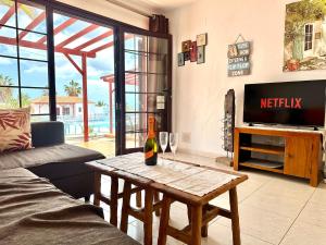 a living room with a bottle of wine on a table at Encantador bungalow con vistas a la piscina in Caleta De Fuste