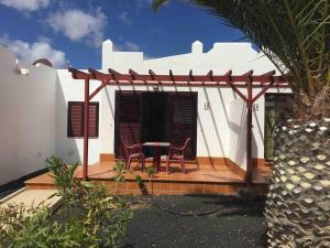 a house with a table and chairs on a porch at Encantador bungalow con vistas a la piscina in Caleta De Fuste