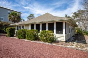 a white house with a porch and bushes at Beasley Beach House in Blue Mountain Beach