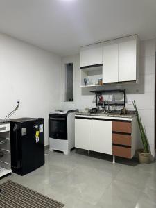 una cocina con armarios blancos y un aparato negro en apartamento recreio 5 min da praia, en Río de Janeiro