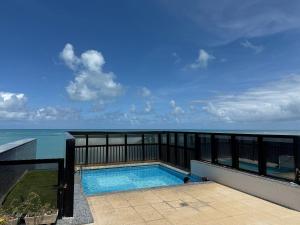 a swimming pool with the ocean in the background at Edificio Neo Apto 401 in Maceió