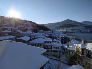 a city with snow covered roofs with the sun in the background at Lakeview Balcony in Kastoria in Kastoria