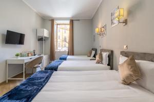 a hotel room with three beds and a desk at Portafortuna GUESTHOUSE - close to COLOSSEUM in Rome