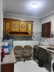a kitchen with wooden cabinets and a sink and chairs at شقق فندقية للعوائل بآرقي مناطق الهرم الرئيسي in Cairo