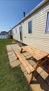 a wooden picnic table in front of a trailer at Buxton's Holiday Home - 'Park Holiday's' complex - St Osyth - Clacton-on-Sea in Saint Osyth