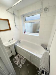 a white bathroom with a tub and a sink at Cute two bedroom house with free street parking in Liverpool