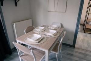 a wooden table with white plates and dishes on it at La parenthèse du sud Parking calme et confort in Valence