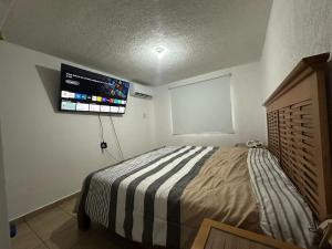 a bedroom with a bed and a tv on the wall at Casa en Acapulco los tulipanes in Acapulco
