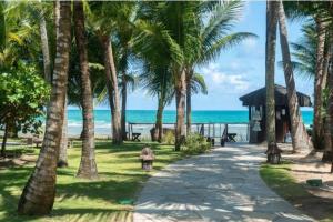a person sitting on a bench next to the beach at Nannai Residence - Muro Alto - Porto de Galinhas in Porto De Galinhas