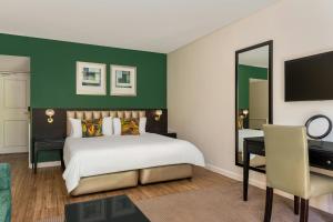 a bedroom with a bed and a desk and a mirror at Lord Charles Hotel, Somerset West, a Tribute Portfolio Hotel in Somerset West