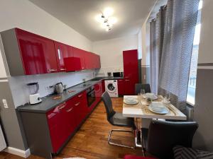 a kitchen with red cabinets and a table with chairs at Schöne 3 Zimmer Wohnung in Top Lage Heidelberg 1 OG in Heidelberg