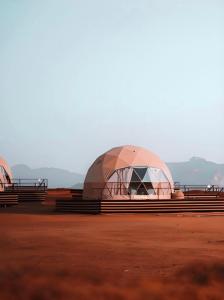 a domed tent in a field with mountains in the background at RUM BUBBLES VIEW lUXURY CAMP in Wadi Rum