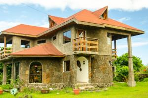 a house with an orange roof on a green field at Cabañas Moai in Hanga Roa