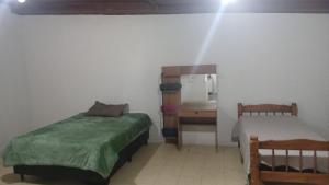 une chambre avec un lit, un bureau et un miroir dans l'établissement Casa Glória macaé, à Macaé