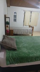 Elle comprend un grand lit avec une couverture verte. dans l'établissement Casa Glória macaé, à Macaé 1 autre photo