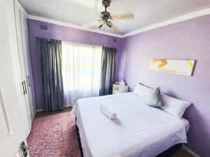 a bedroom with purple walls and a white bed at Tranquil Coastal Home with Pool Family-Friendly Stay in Uvongo Beach +8 photos