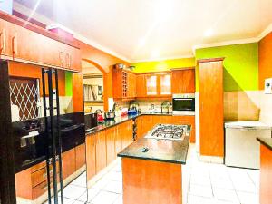 a large kitchen with wooden cabinets and black appliances at Tranquil Coastal Home with Pool Family-Friendly Stay in Uvongo Beach