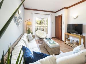a living room with white furniture and a flat screen tv at Charming apartment in Benagil with pool in Benagil