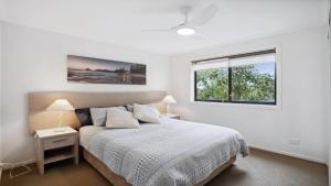 a white bedroom with a bed and a window at 306 South Pacific Apartments in Port Macquarie +3 photos