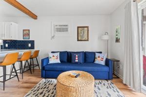a living room with a blue couch and a kitchen at Renovated 1-Bedroom Condo with Pool, Bikes, & Beach Access in North Ocean City, MD in Ocean City