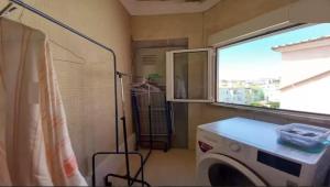een wasruimte met een wasmachine en een raam bij Sams Healing Guest House in Amadora