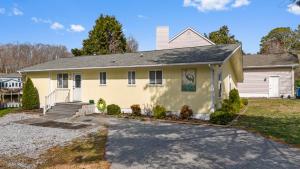 a yellow house with a driveway in front of it at Heron Hideaway Canal-Front 3-Bedroom Home in Ocean Pines, MD, Near Ocean City Beaches in Berlin