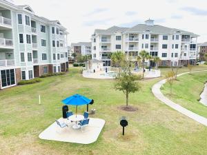 an aerial view of an apartment yard with chairs and a blue umbrella at Calming & Relaxing condo in the center of MB in Myrtle Beach