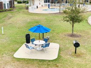 a table and chairs with a blue umbrella on a yard at Calming & Relaxing condo in the center of MB in Myrtle Beach
