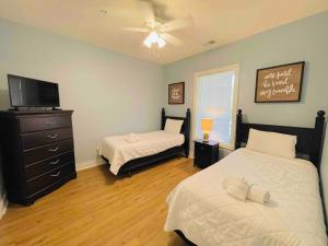 a bedroom with two beds and a tv and a dresser at Calming & Relaxing condo in the center of MB in Myrtle Beach