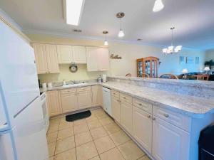 a kitchen with white cabinets and a white refrigerator at Calming & Relaxing condo in the center of MB in Myrtle Beach