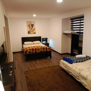 a bedroom with two beds and a television in it at Suite La Pergola - El Renacimiento Suites in Cuenca