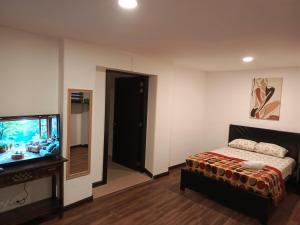 a bedroom with a bed and a flat screen tv at Suite La Pergola - El Renacimiento Suites in Cuenca