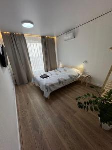 a bedroom with a bed and a wooden floor at Стильная однокомнатная квартира in Almaty +2 photos