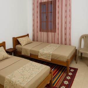 a room with two beds and a chair at Dar El Yasamine in Houmt Souk