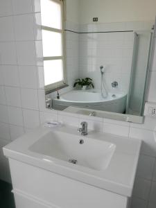 a white bathroom with a sink and a tub at Guesthouse Flora in Lodi