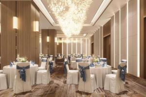 a banquet hall with white tables and chairs and a chandelier at Ramada Encore by Wyndham Gurugram Dwarka Expressway in Gurgaon +23 photos