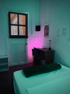 a bedroom with a bed and a desk with a pink light at Hostal Mamaquilla in Pasto