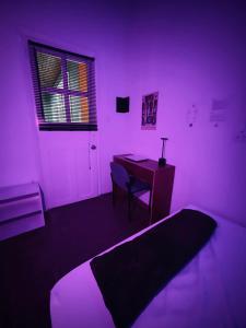a bedroom with a bed and a desk with a purple light at Hostal Mamaquilla in Pasto +46 photos