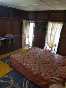 a bedroom with a large bed in a room at Roomstay "Ghumah Uwan" bilik kayu in Batu Kikir