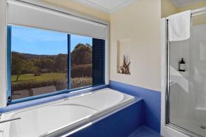 a bathroom with a tub and a large window at Boutara Holiday House in Falmouth +37 photos