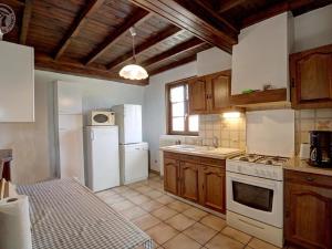 kuchnia z białymi urządzeniami i drewnianymi szafkami w obiekcie Gîte familial avec cheminée, jardin et espace jeux près de Chazelles-sur-Lyon et St-Galmier - FR-1-496-281 w mieście Saint-Médard-en-Forez