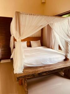 una camera con letto a baldacchino con lenzuola e cuscini bianchi di ASTAGINA VILLA ad Ubud