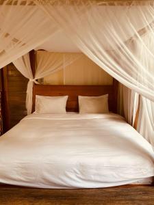 una camera da letto con un letto bianco con baldacchino di ASTAGINA VILLA ad Ubud Altre 20 foto