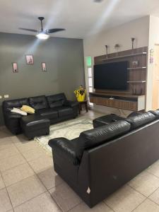 a living room with black leather furniture and a flat screen tv at Casa Ramos in Itanhaém