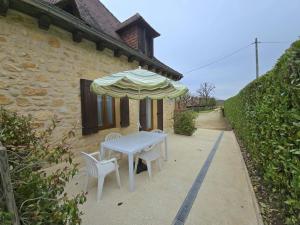 Charmante maison à Domme avec WiFi près de la Dordogne - FR-1-616-66 في دوم: طاولة وكرسيين ومظلة أمام المبنى