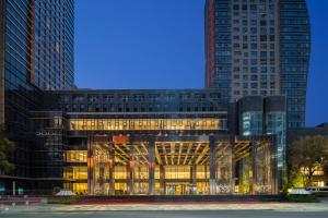 a building with a lit up facade with tall buildings at YTL OuYue International Hotel in Wenzhou